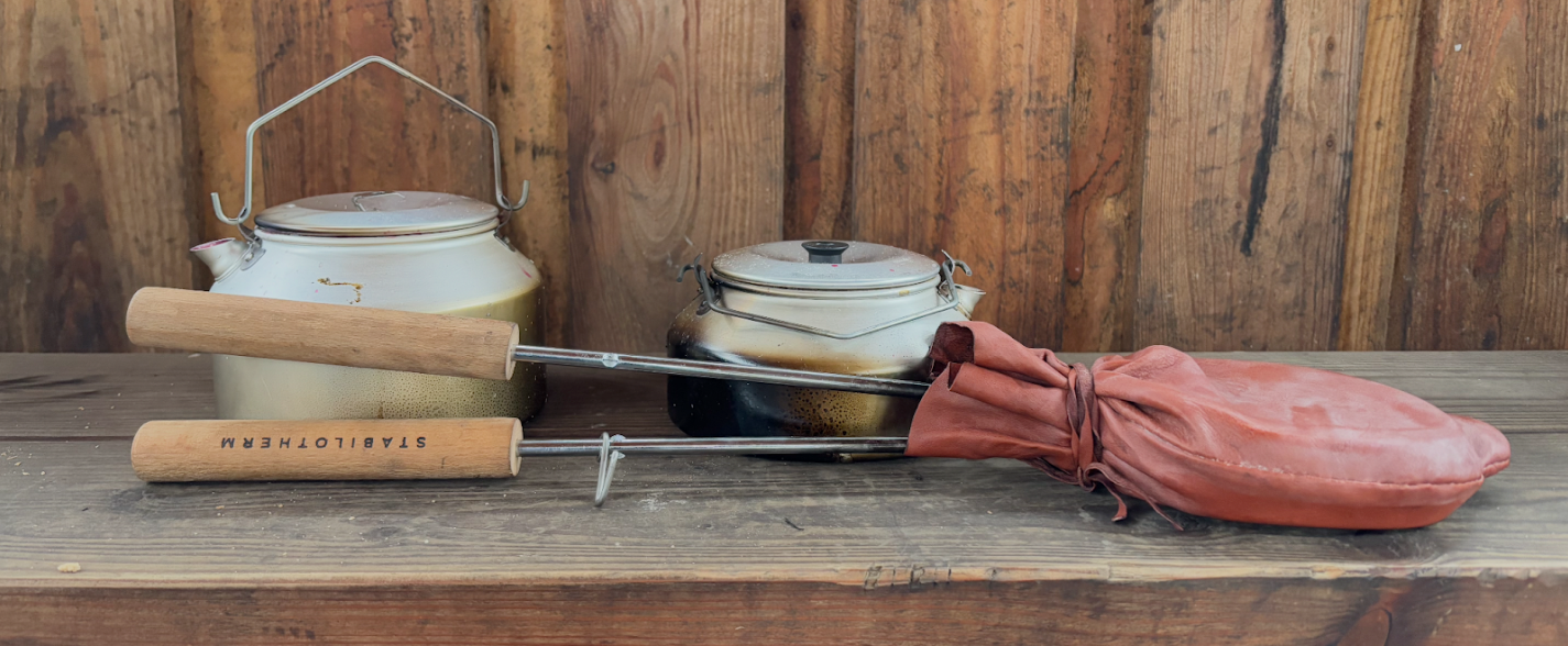 Kettles for cowboy coffee and blueberry soup, next to the packed-up sandwich iron