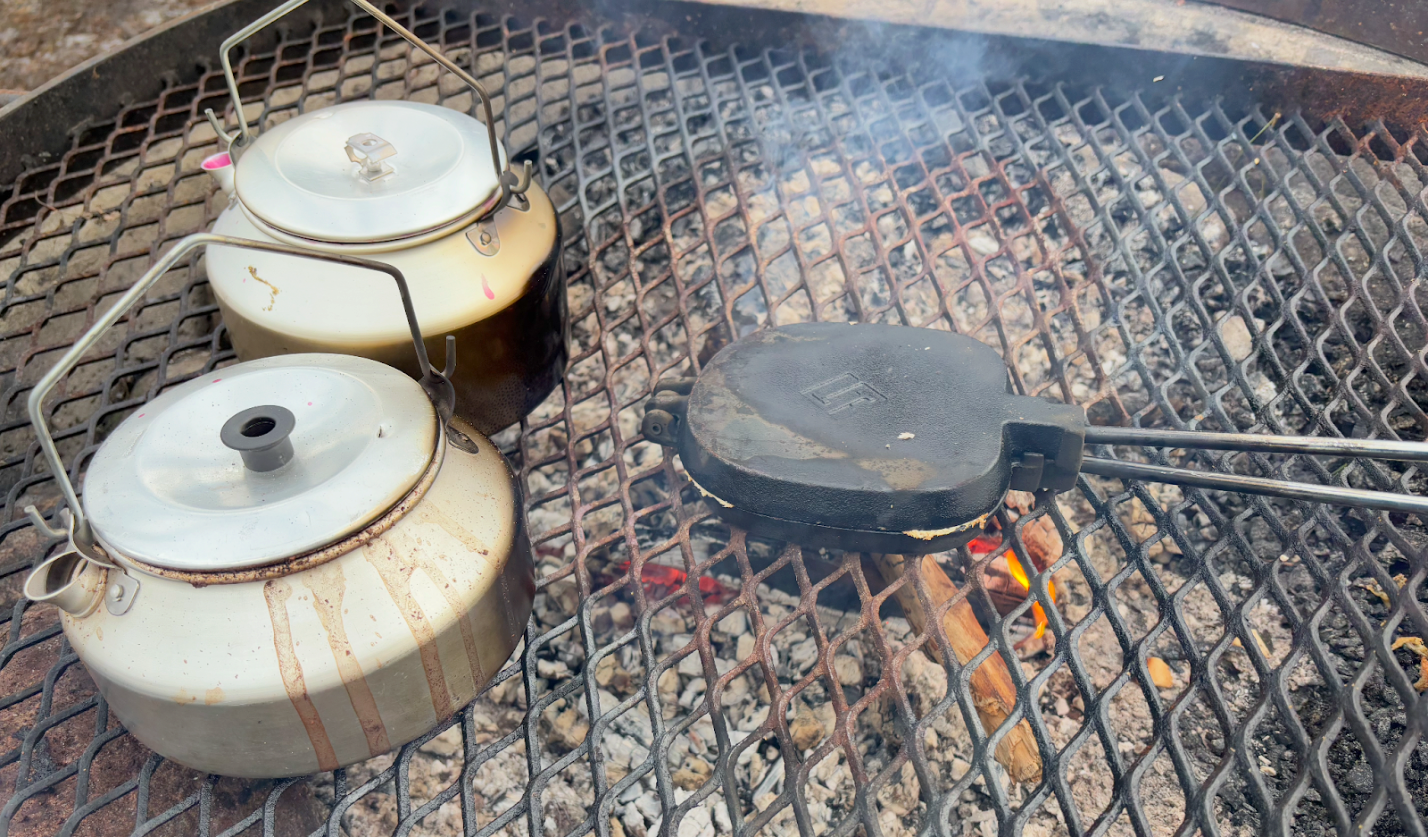 Coffee, blueberry soup, and sandwich iron over the fire